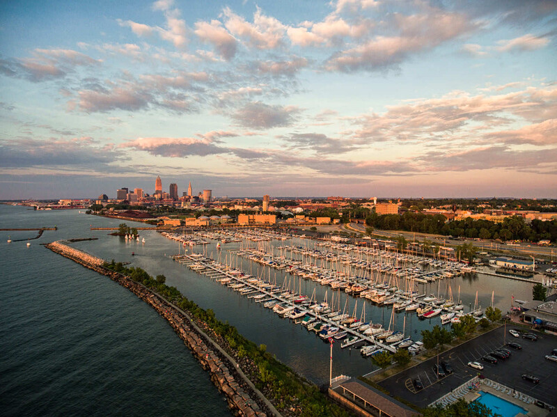 Aerial view of a crowded marina at sunset with a city skyline in the background