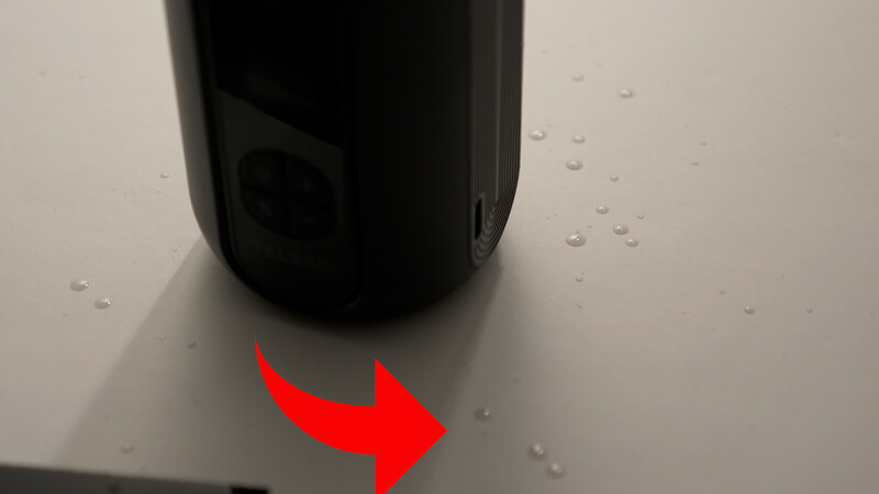 Water droplets on a surface with a black cylindrical object and a red arrow pointing right